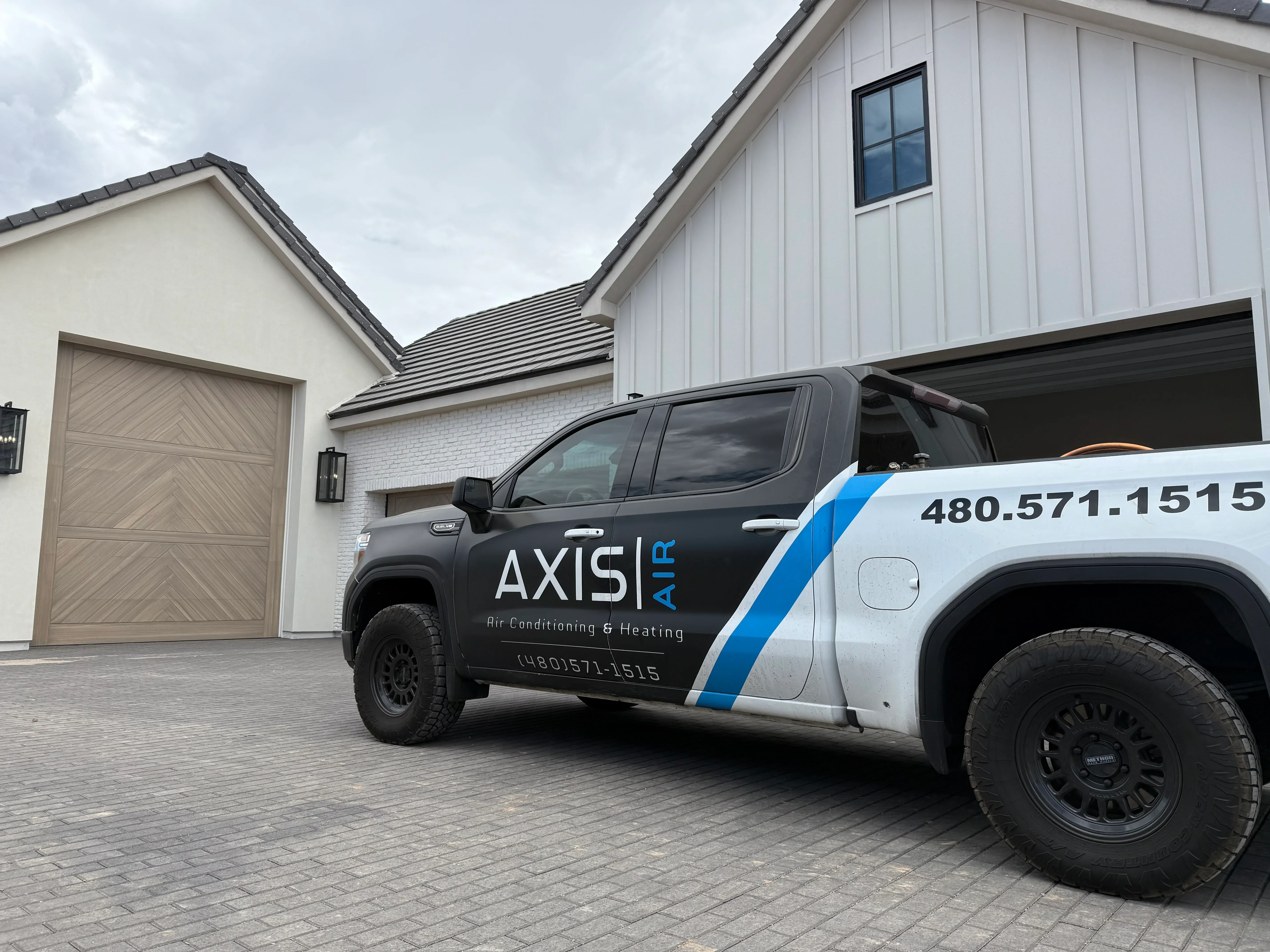 Service truck parked at modern home with white siding and metal roof