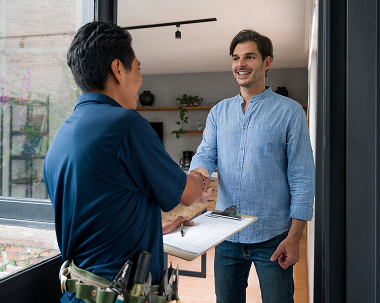an hvac technician shakes a customer's hand and their front door